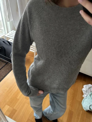 Grå stickad tröja med rund hals - Mysig grå stickad tröja med rund halsringning och långa ärmar.