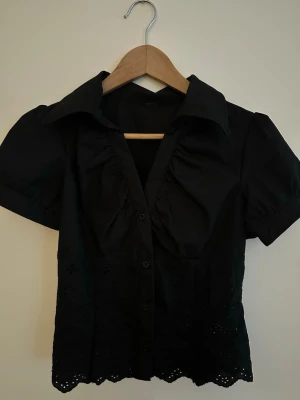 Svart topp med broderad kant - Snygg svart topp med spets, använd fåtal gånger, köpt utomlands, nypris 300kr, mitt pris: 200💕