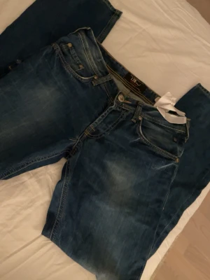 Blå jeans från LTB med slitningar - Snygga blå jeans från LTB med klassisk femficksmodell och coola slitningar på både fram- och baksida. Jeansen har normal midja, raka ben och kontrastsömmar. Perfekta för dig som gillar en avslappnad men trendig stil.
