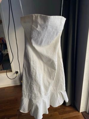 Vit axelbandslös klänning från Guess - Supergullig axelbandslös klänning med volangkant nedtill. Vintage från Guess. Klänningen är stretchig och har gummi kant på insidan upptill så den håller sig uppe! Passar xs-s