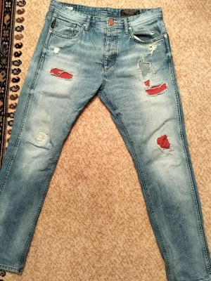 Jack & Jones Erik Anti-Fit röda jeans - Jack & Jones Erik Anti-Fit jeans i röd/burgundy tvätt. 100cm långa och 45cm breda Avslappnad anti-fit passform med bekvämt, lätt avsmalnande ben. Klassisk 5-ficksdesign i denim av bomull. Bra skick – inga större defekter. Perfekta för streetwear, vardag eller vintageinspirerade outfits.Märke: Jack & Jones Modell: Erik Anti-Fit Färg: Röd / Burgundy Passform: Anti-Fit / Avslappnad Skicka gärna meddelande för mått eller fler bilder. 