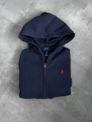 Ralph Lauren Zip - Marinblå med röd brodering - Säljer nu min Ralph Lauren Hoodie då jag inte längre har någon användning för den. Tröjan är i myclet bra skick men lite liten i storlek. Skriv gärna vid funderingar när det gäller plagg eller pris!🔥