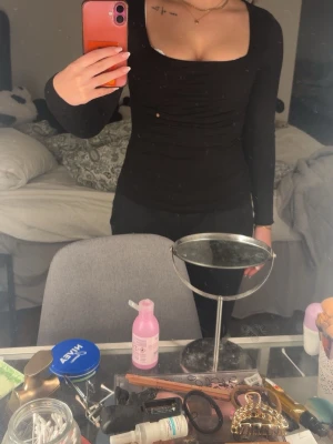 Svart långärmad topp med fyrkantig ringning - Snygg svart långärmad topp med fyrkantig ringning och figurnära passform. Perfekt att styla med både jeans och kjol för en trendig look. Tunn och stretchig, passar dig som gillar en enkel men stilren vibe.