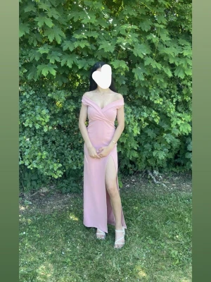 Ljusrosa off shoulder klänning - Säljer en ljusrosa klänning med off shoulder. Klänningen har en hög slits på ena sidan och figurnära passform. Nypris 500kr, endast använd en gång. Passar som XS också 