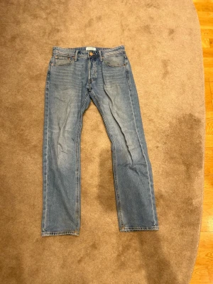 Blå raka jeans från Jack&Jones - Klassiska blå jeans från Jack&Jones i modellen comfort/mike med rak passform och fem fickor i storlek 30/30. Jeansen har en ljus tvätt med subtila slitningar och kontrastsömmar. Pris kan diskuteras!! Vid minsta fundering är det bara att höra av sig!