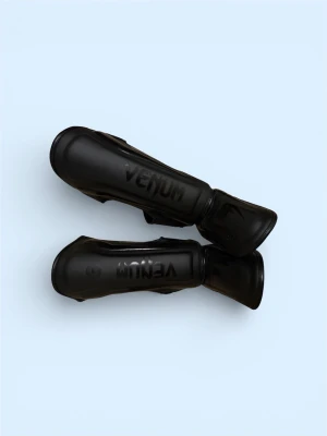 Svarta benskydd från Venum - Säljer ett par svarta benskydd från Venum, knappast använda och perfekta för kampsport och träning. Tillverkade i slitstarkt syntetläder med vaddering för extra skydd. Snyggt präglad logga på framsidan och justerbara kardborreband för bra passform.