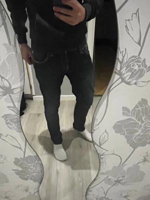 Mörkblå slim jeans från Nudie Jeans - Säljer ett par mörkblå slim fit jeans från Nudie Jeans med klassiska orange sömmar och broderade bakfickor. Jeansen har normal midja och raka ben, tillverkade i denim med snygg tvätt. Perfekta för en stilren och avslappnad look. Pris går att förhandla!