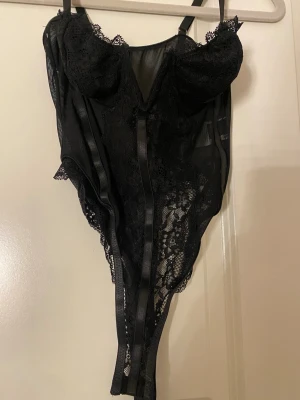 Svart spetsbody - Snygg svart body i spets med tunna, justerbara axelband och bygelkupor. Perfekt för fest. Endast testad! 