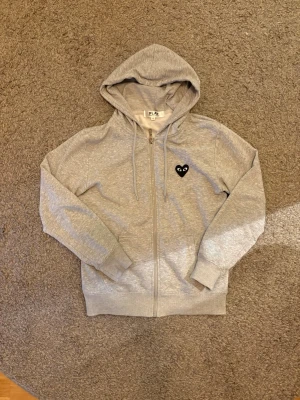 Comme des Garçons hoodie - Snygg grå comme des garcon hoodie med tryck fram och bak. Det är meningen att den ska vara rätt så tunn. Knappt använd. Skriv ifall det finns fler frågor.