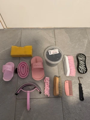 Rosa hästborstkit med tillbehör - Säljer ett komplett kit med hästborstar och tillbehör i rosa och gult. Innehåller olika borstar, hovkrats, svamp, mankam, gummisnoddar och en svansborste med zebramönster. Perfekt för dig som vill ha allt för hästskötseln samlat i ett set.