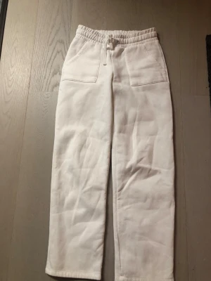 Vita mjukisbyxor med raka ben - Säljer ett par vita mjukisbyxor med raka ben och resår i midjan. Byxorna har två stora fickor fram och två bakfickor. Tillverkade i mjukt och skönt material. Passar dig som gillar enkel och clean stil. Strl XS/S