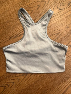 Grå/silver sport-bh från The Couture Club - Snygg grå sport-bh från The Couture Club med korsade axelband i ryggen. Tillverkad i ett stretchigt och mjukt material som sitter skönt mot kroppen. Perfekt för träning eller chill dagar. Knappt använd så mycket fint skick 