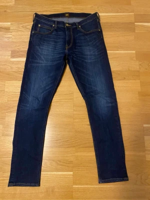 Mörkblå jeans Lee - Snygga mörkblå jeans från Lee med klassisk femficksmodell och kontrastsömmar. Jeansen har en rak passform.