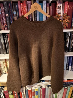 Brun stickad tröja från Gina Tricot - Mysig brun stickad tröja från Gina Tricot i ullblandning. Tröjan har en avslappnad passform, rund halsringning och ribbade muddar vid ärmslut och nederkant. Perfekt för lager på lager under kyliga dagar.