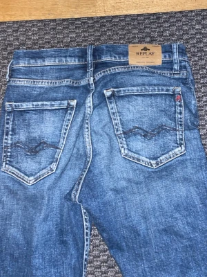 Blå raka jeans från Replay - Snygga blå jeans från Replay med klassisk femficksmodell och raka ben. Jeansen har en lätt tvättad look och detaljerade sömmar på bakfickorna. Perfekta för en avslappnad stil.