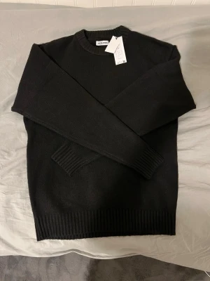 Svart stickad tröja från Jack and Jones - En stilren svart stickad tröja från Jack and Jones med rund halsringning och ribbade muddar vid ärmslut och nederkant. Perfekt för lager-på-lager och enkel att matcha med andra plagg. Klassisk passform och mjukt material. Storlek XS men känns som S/M