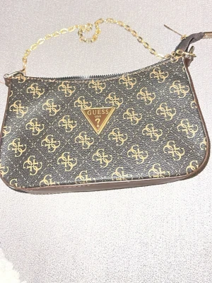 Handväska - Snygg kuvertväska från Guess (ej äkta). Lite missfärgad i tyget på insidan av själva väskan, syns ej utifrån. Därav det billiga priset☺️