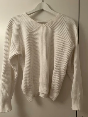 Vit stickad tröja från Filippa K - Snygg vit stickad tröja från Filippa K i storlek S. Tröjan har ett ribbstickat mönster, rund halsringning och långa ärmar. Perfekt för lager-på-lager och enkel att matcha med jeans eller kjol.
