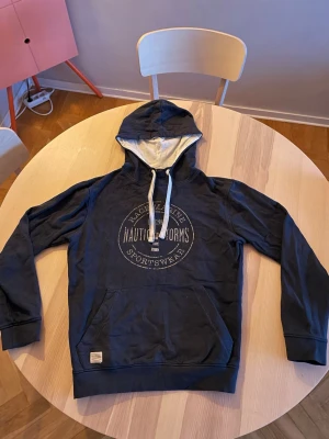 Marinblå hoodie från Race Marine - Snygg marinblå hoodie från Race Marine med vitt tryck på bröstet och vita dragsnören i huvan. Hoodien har en klassisk känguruficka framtill och mjukt innerfoder i huvan. Perfekt för en avslappnad och sportig stil.