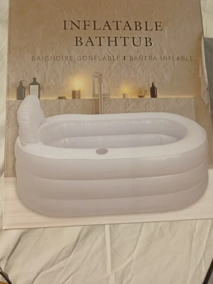 Uppblåsbar badbalja vit - Praktisk uppblåsbar badbalja i vit plast. Perfekt för dig som vill ha ett portabelt badkar hemma eller på resan. Enkel att blåsa upp och tömma, med ryggstöd för extra komfort. Rymmer en vuxen person och tar liten plats när den är nedpackad. Den är bara använd en gång så den är i ett nytt skick.