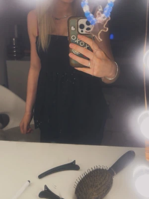 Svart topp med tunna band och volang - Fin svart topp med tunna axelband  och volanger med mönster detaljer. Toppen har en lätt utsvängd passform och är perfekt inför sommaren.  Materialet känns mjukt mot huden. Det är storlek S men är lite lång i modellen och stretchig så passar förmodligen större storlekar med. Skriv privat ifall önskas fler bilder eller frågor!!❤️