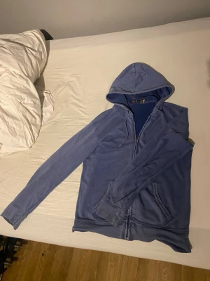  Polo Ralph Lauren hoodie  - Snygg blå hoodie från Polo Ralph Lauren med dragkedja framtill och två fickor. Klassisk huva och mjukt material som känns skönt mot huden. Perfekt för en avslappnad och stilren look. Pris går och diskutera vid snabb affär