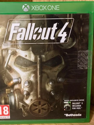 Fallout 4 till Xbox One - Fallout 4 till Xbox One är ett actionrollspel med öppen värld där du utforskar en postapokalyptisk värld. Omslaget är grönt med en ikonisk power armor-mask på framsidan. Spelet är på engelska och har PEGI 18-märkning.