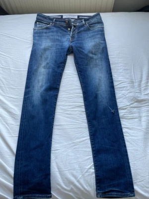 Mörkblå jeans från Jacob Cohen - Säljer ett par klassiska blå jeans från Jacob Cohen modell 622. Jeansen har snygga slitningar framtill och kontrastsömmar. Perfekt för en avslappnad stil. Pris går att diskuteras!