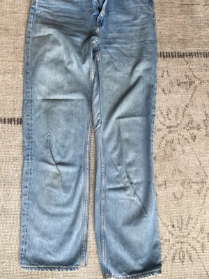 Blå raka jeans från Weekday - Säljer ett par ljusblå jeans från Weekday, modell Voyage. Jeansen har raka ben, klassisk femficksdesign och dragkedjegylf. Tillverkade i bomull med snygga kontrastsömmar. Perfekta för en avslappnad och trendig look.