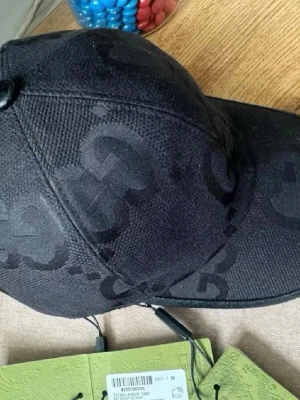 Svart keps från Gucci med GG-mönster - Snygg svart keps från Gucci med det klassiska GG-monogrammet ton-i-ton över hela kepsen. Kepsen har böjd skärm och är tillverkad i ett slitstarkt tygmaterial. Perfekt accessoar för en trendig streetstyle-look.