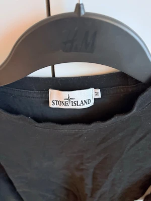Svart långärmad tröja Stone Island - Säljer en svart långärmad tröja från Stone Island med rund hals och klassisk logotyp på ärmen. Tröjan har enkel design och är tillverkad i mjukt bomullstyg, är storlek M men sitter som S, säljs nu för endast 299kr!