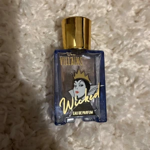Disney Villains Wicked Eau de Parfum - Parfymflaska från Disney Villains-serien med texten 'Wicked'. Flaskan är fyrkantig i blått glas med gulddetaljer och ett guldigt lock. Snygg design med en krona på framsidan, perfekt för dig som gillar unika och temainspirerade dofter.