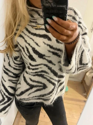 Zebramönstrad stickad tröja - Snygg stickad tröja med zebramönster i svart och vitt. Tröjan har hög krage och är tillverkad i ett mjukt, fluffigt material. Perfekt för dig som vill sticka ut med ett djurinspirerat plagg. Långärmad och avslappnad passform. Lånade bilder!💞