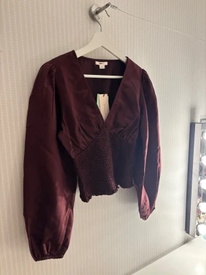 Vinröd blus - Helt ny blus från Gina Tricot med puffiga ärmar och v-ringning. Superfin och passar alla tillfällen! Säljer då den tyvärr inte passar mig🥰
