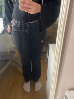 Svarta raka jeans med slitning - Säljer ett par svarta jeans och flare passform liten slipning på och en liten slitning på ena låret och på knäna Jeansen har klassisk femficksdesign och hög midja. Perfekta till en avslappnad och trendig look.