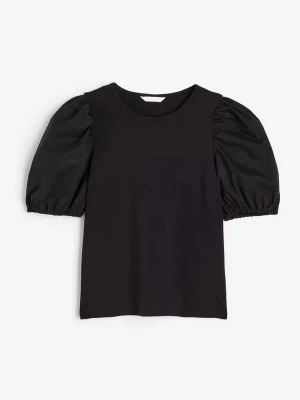 Svart topp med puffärmar från H&M - Snygg svart topp från H&M med puffiga korta ärmar och rund halsringning. Toppen har en enkel, stilren design och är gjord i mjukt bomullsmaterial. Perfekt för dig som vill ha en trendig och bekväm look.