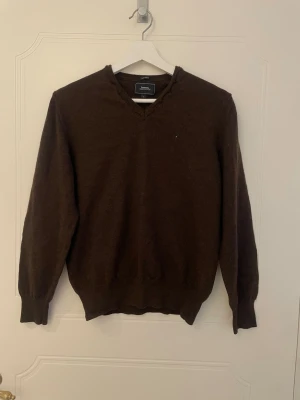 Brun v-ringad tröja - Brun stickad tröja från Boomerang  Storlek L men liten i storleken (44cm axelbredd och 58cm längd) 100% Merino ull  obs! katt finns i hemmet