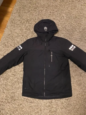 Svart Sail Racing vinterjacka  - Svart vinterjacka från Sail Racing, köpte den i Sail Racing för ett år sen med andra ord nästan helt ny. Jag säljer den för ska ta över min pappas jacka. Köpte för 3,2 med rea. 
