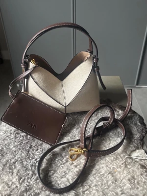 Populära beige/bruna ZARA väskan. - Mycket populär & eftertraktad slutsåld ZARA handväska. Beige med bruna tydliga dekorativa sömmar & brunt handtag. Tillkommer en brun avtagbar axelrem samt en avtagbar mini plånbok (zara loggan på). Gott skick, några små defekter men påverkar inte helheten, några små svarta fläckar inuti & en liten fläck bak på väskan (se sista bilderna). 🤎
