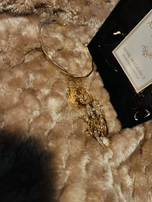 Guldigt armband och guldiga ringar - Snyggt armband i guld med matchande ringar till, ringarna är  glittrande och har diamanter. Armbandet har en öppen design som passar alla handleder. Perfekt accessoar för att lyfta din outfit.