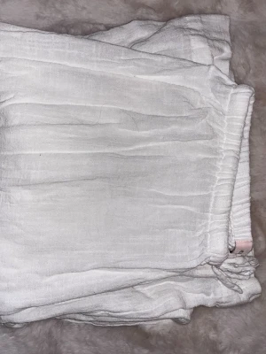 Vita linnebyxor från Nelly - Säljer ett par vita linnebyxor från Nelly i storlek XS. Byxorna har resår i midjan med knytband och är gjorda i ett luftigt linnetyg. Perfekta för en avslappnad och stilren look.