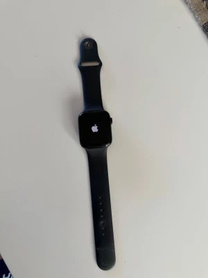 Apple Watch svart smartklocka - Snygg svart Apple Watch SE Gen 2 med rektangulär skärm och silikonarmband. Klockan har en modern design och passar perfekt för dig som vill ha koll på notiser, träning och hälsa direkt på handleden. Inga repor eller defekter! 