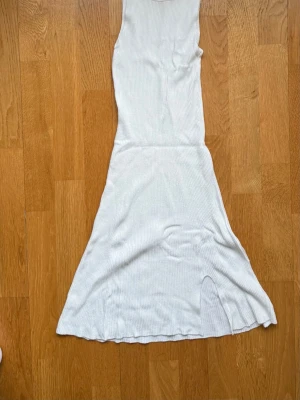 Vit ribbad miniklänning Pull&Bear - Säljer en vit ribbad miniklänning från Pull&Bear. Klänningen har en smickrande passform, rund halsringning och en liten slits nedtill för extra rörelsefrihet. Perfekt för en clean och enkel look.