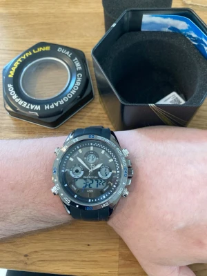 Martyn Line Dual Time Chrono 47mm - Säljer en helt ny oanvänd kvalitetsdykare från brittiska Martyn Line i absolut nyskick. Plasten sitter kvar på glaset. Fungerar utmärkt, originalarmband i slittåligt gummi som passar alla, dagvisare, vattentät, självlysande visare, japanskt urverk, digitalklocka, två tidszoner, tidtagarur, kronograf osv. Behöver bara nytt batteri. Fås i originalförpackning, med certifikat och tagg.  Nypris: 2700 SEK Begagnat pris: < 1200 SEK Mitt pris: 789 SEK  Skickas alltid snabbt och spårbart. Skriv vid frågo