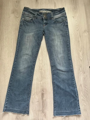 Blå bootcut jeans med slitningar - Säljer ett par blå bootcut jeans med snygga slitningar, super fina men används tyvärr inte