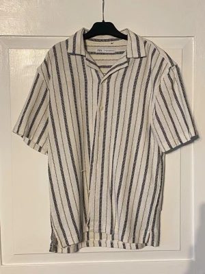 Randig skjorta Zara  - En kortärmad randig skjorta med häftig struktur i tyget från Zara. Ett plagg man verkligen inte kan gå fel med nu i sommar. Storlek M, sitter M. Säljer billigt då jag desperat behöver plats i garderoben 😅