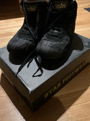 Svarta Star Footwear high top sneakers - Säljer mina svarta Star High Tops från Star Nutrition i väldigt fint skick! Använda endast inomhus och ser nästan nya ut. De har en tunn och stabil sula som ger perfekt kontakt med golvet – superbra för tunga lyft som knäböj och marklyft!