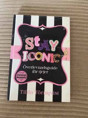 Stay Iconic: Överlevnadsguide för tjejer - En färgstark bok med titeln 'Stay Iconic: Överlevnadsguide för tjejer' av Tilda Törnqvist. Omslaget har svartvita ränder, rosa detaljer och lekfulla bokstäver i olika färger och mönster. Perfekt för dig som vill ha inspiration och tips i vardagen.
