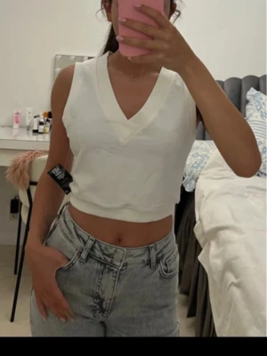 Vit croppad linnetopp med v-ringning - Säljer en stilren vit croppad linnetopp med breda axelband och djup v-ringning. Toppen har en enkel och clean look som passar perfekt till jeans eller kjol. Materialet känns mjukt och bekvämt mot huden.