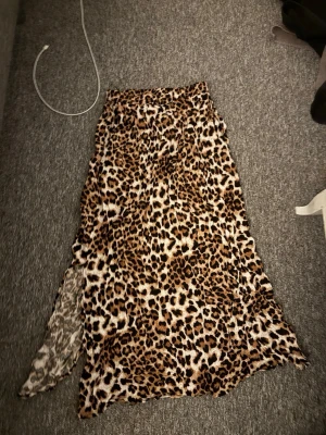 Leopardmönstrad långkjol med slits - Säljer en snygg långkjol med leopardmönster och slits på sidan. Kjolen är aldrig använd och säljes i storlek S 